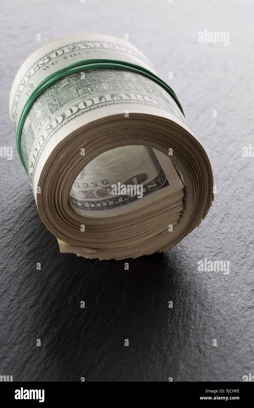 roll dollars on the black rock background. Stock Photo