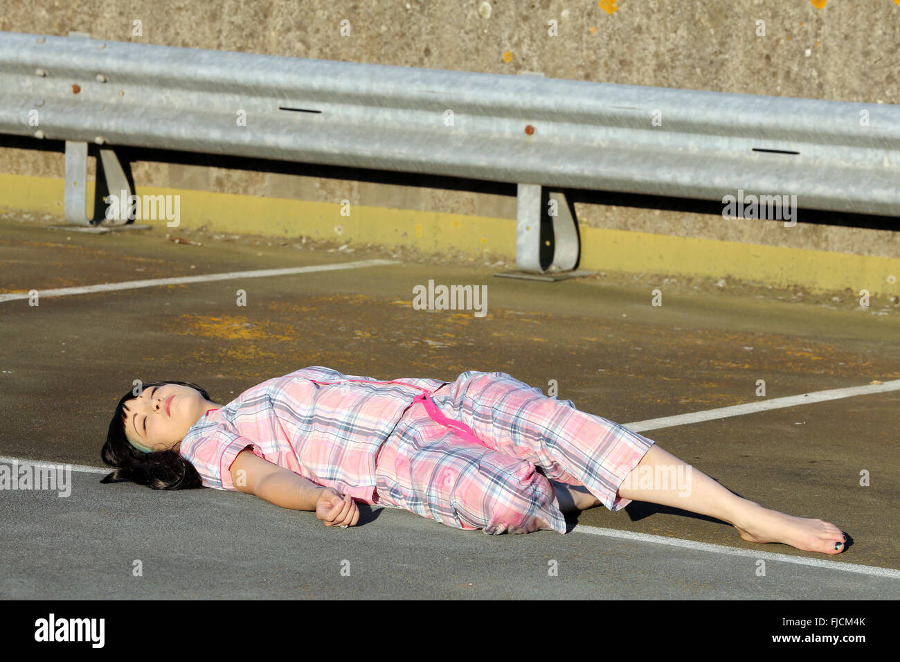 July 2015 Young woman playing dead in her pajamas on top of a multi