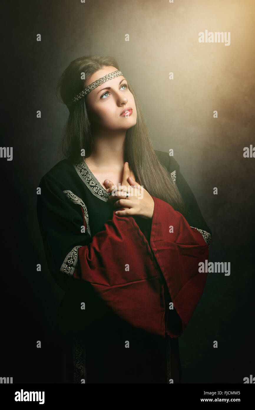 Beautiful medieval woman praying in soft holy light . Historical and religion Stock Photo