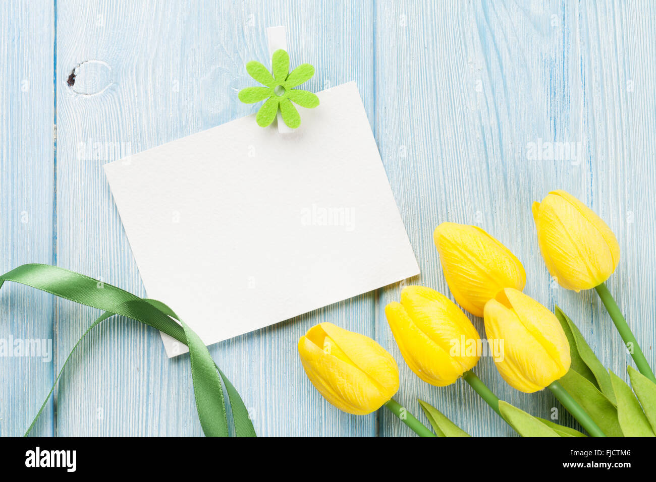 Easter greeting card and yellow tulips over wooden background with copy ...