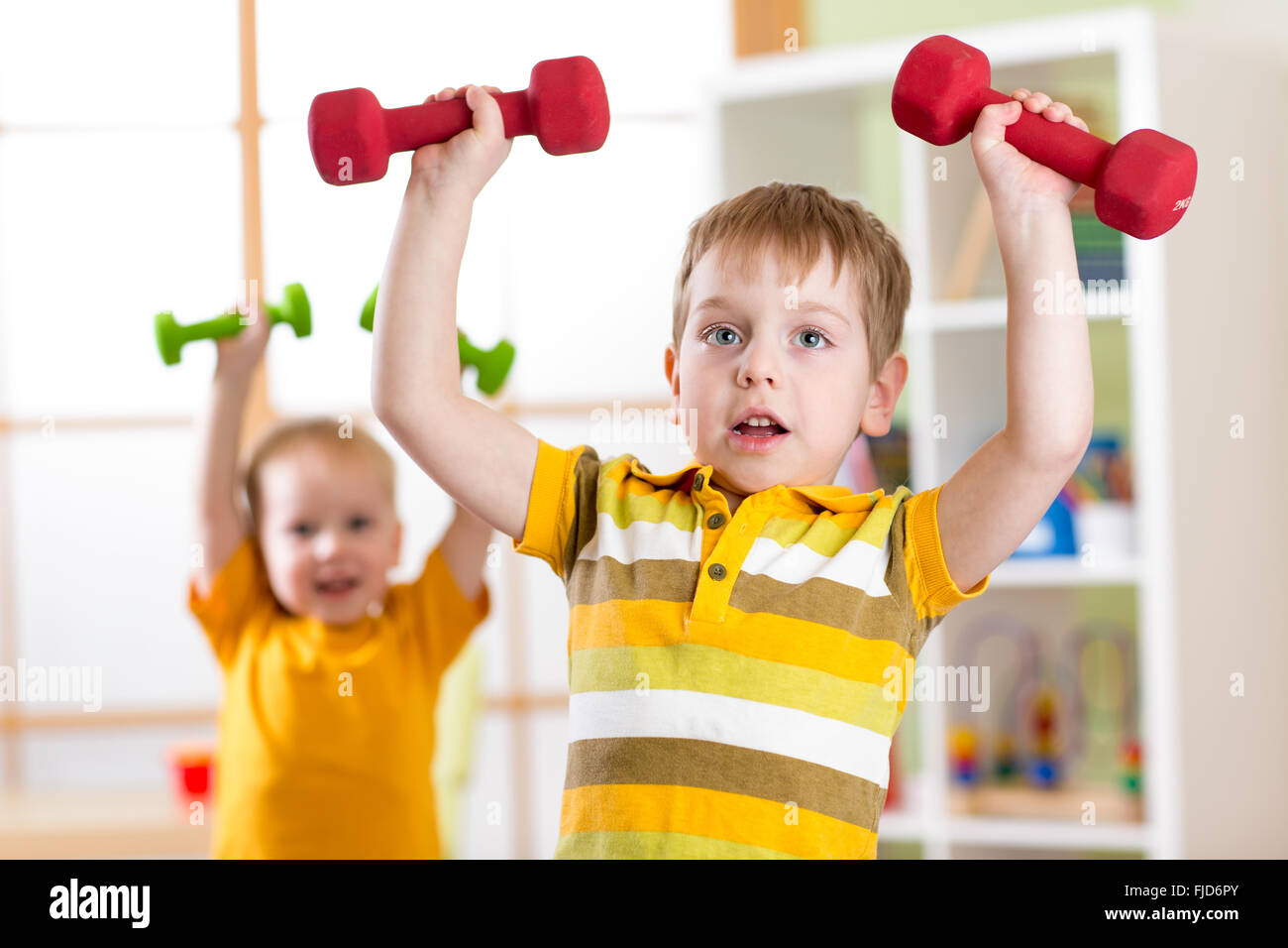 Little children boys exercising with dumbbells at home. Healthy life, sportive kids. Stock Photo