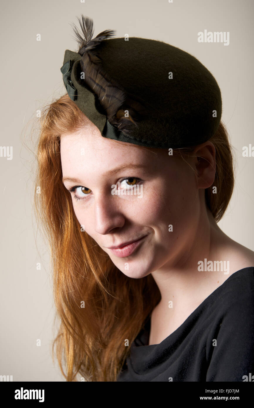 Redhead smiling cheekily in green feathered hat Stock Photo