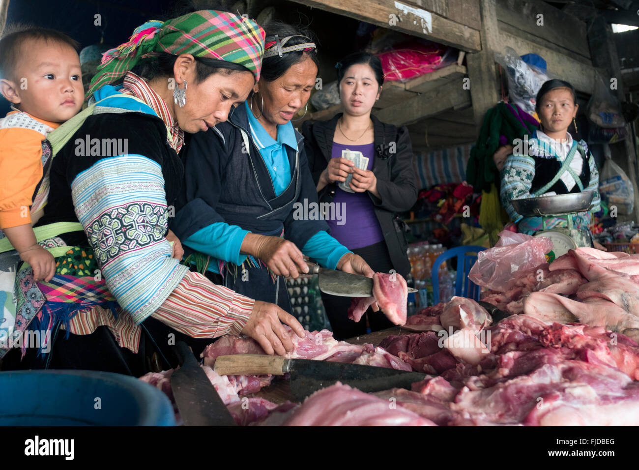 Hmong women buy meat and offal at a market in the northern Vietnam village of Ta Giang Phing. Stock Photo
