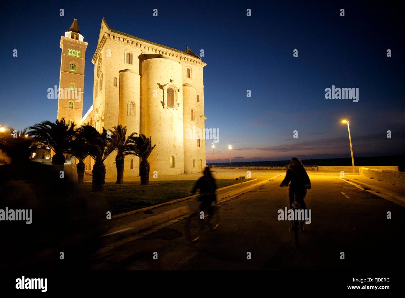 Two cyclist pass St. Nicholas the Pilgrim Cathedral, Trani, Bari Province, Puglia, Italy at night Stock Photo