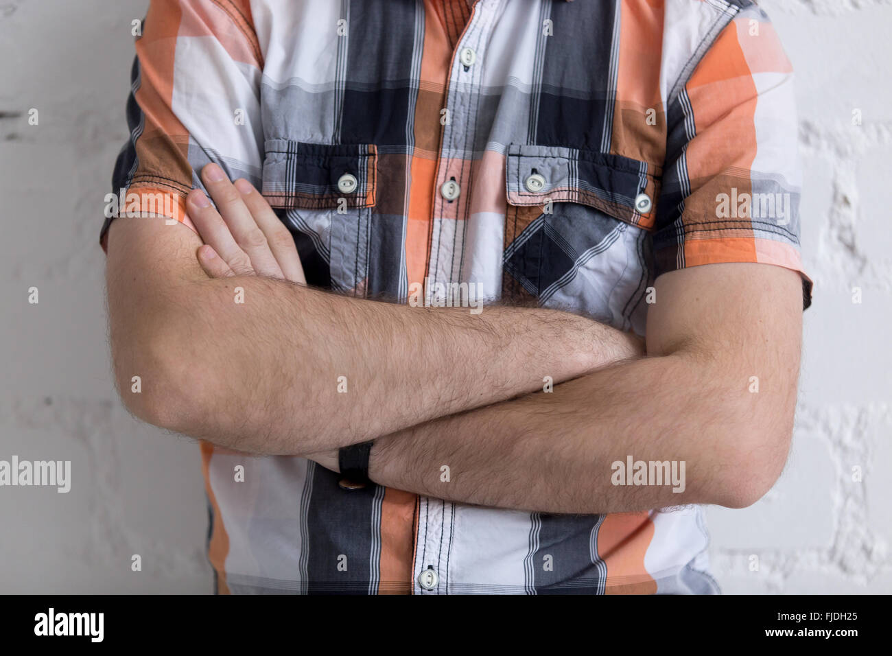 Casual young man standing with arms crossed on his chest, nonverbal communication concept, close-up Stock Photo