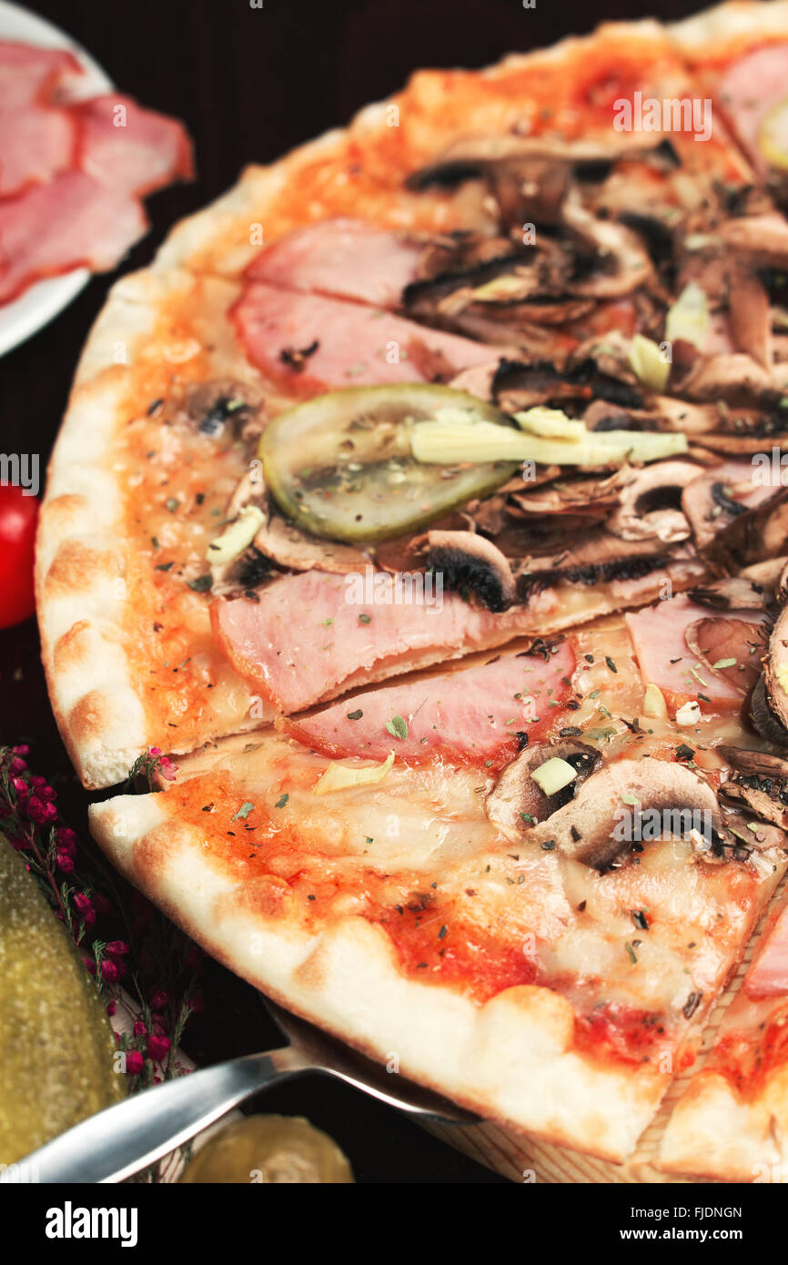 Delicious sliced pizza with meat. cucumbers and mushrooms. Shallow depth of field Stock Photo