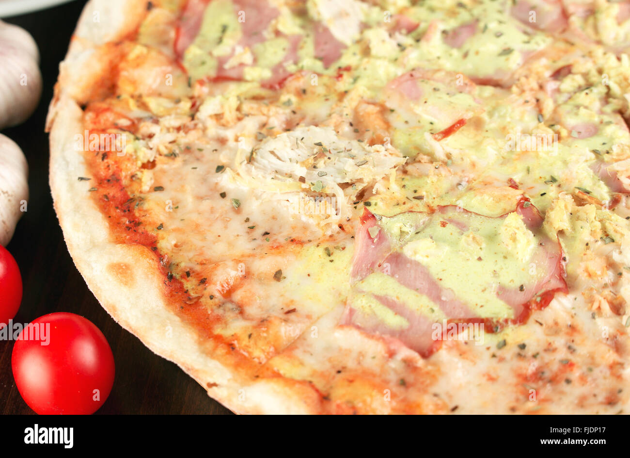 Tasty italian pizza with ham and chicken close up. Shallow depth of field Stock Photo