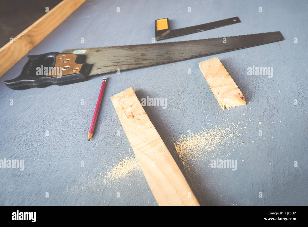 Close focus onto the cracked woods on the table. There are pencil, saw and ruler beside. Stock Photo