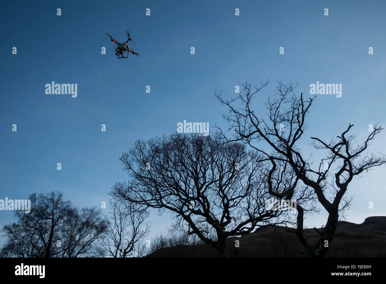 A radio controlled Drone Quadcopter flying at dusk. Stock Photo