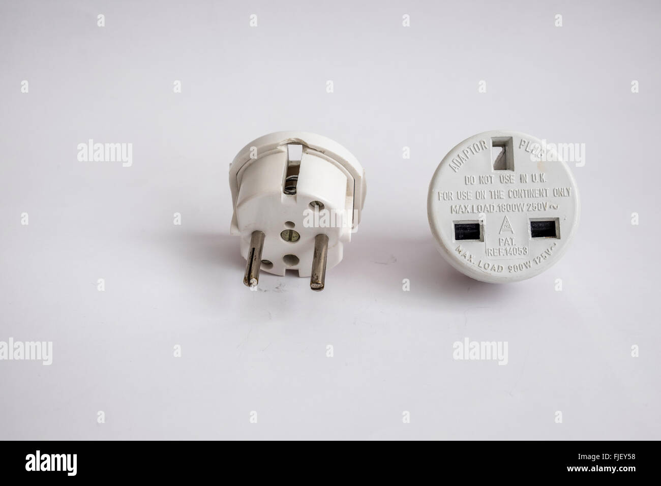 Mains adapter plug with 13 amp 3 pin socket converted to 2 round pins for use in Europe. Stock Photo