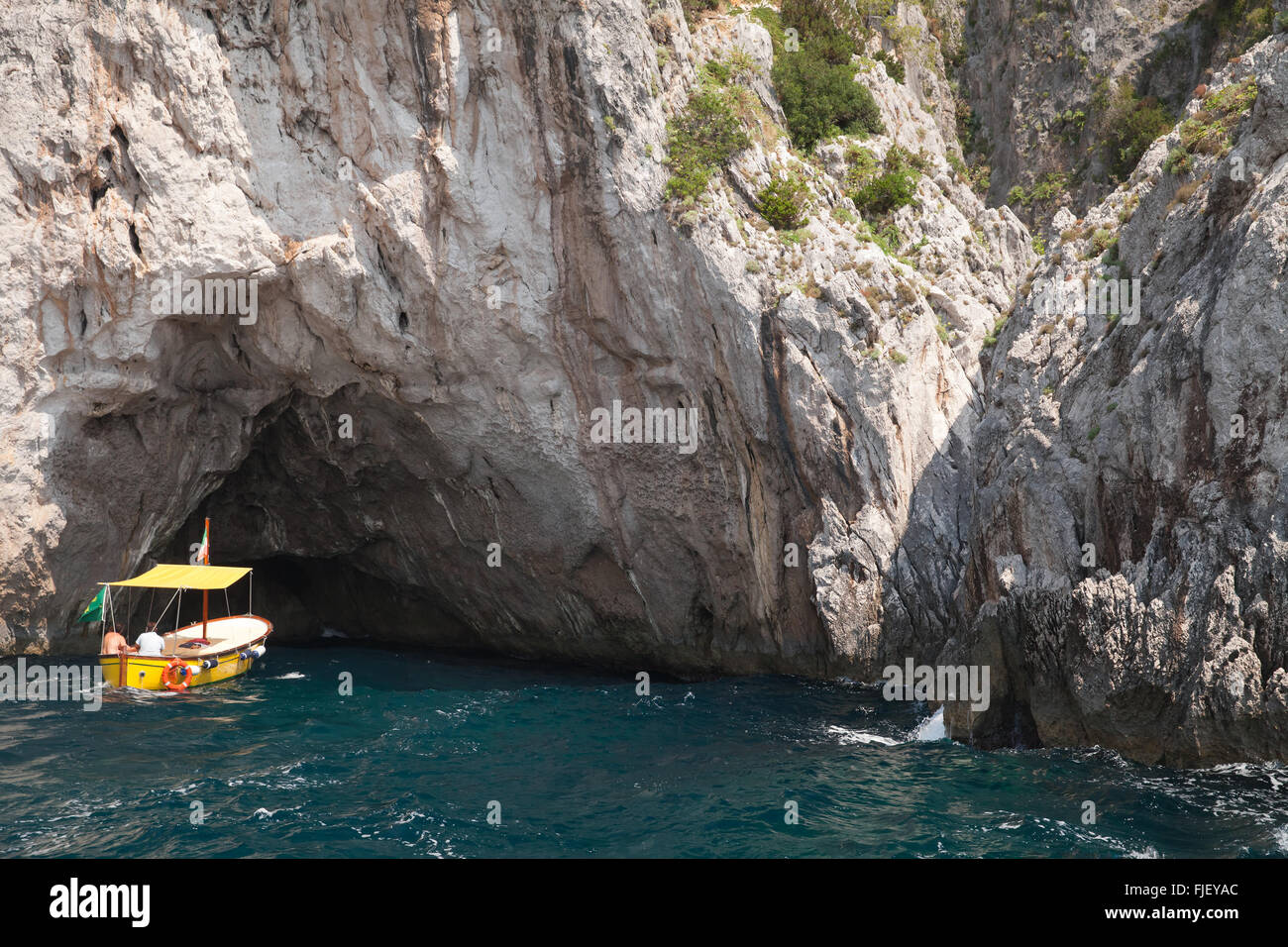 Small recreation motorboat enters the grotto in coastal rocks of Capri island, Italy Stock Photo