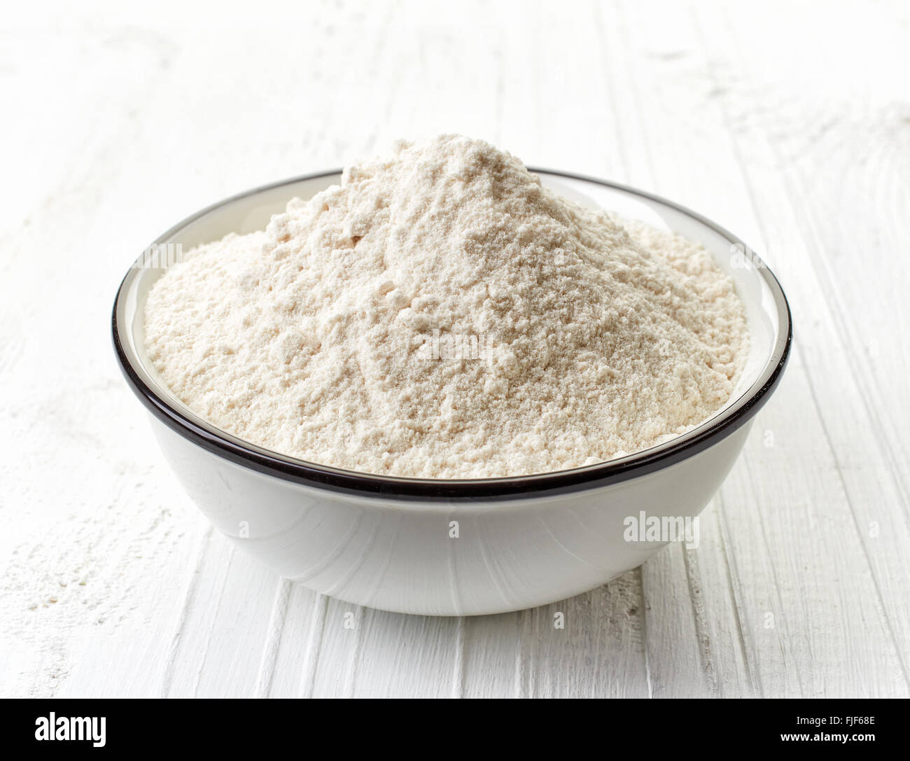 Bowl of white flour on white wooden table Stock Photo