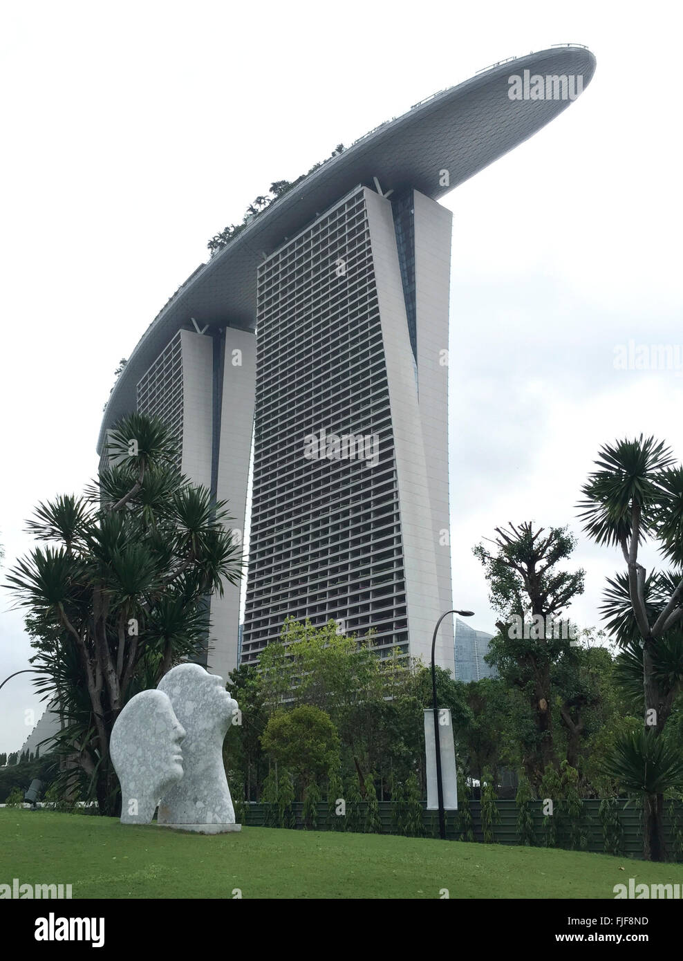 Two statues of heads looking up to the Marina Bay Sands Resort Hotel in Singapore Stock Photo