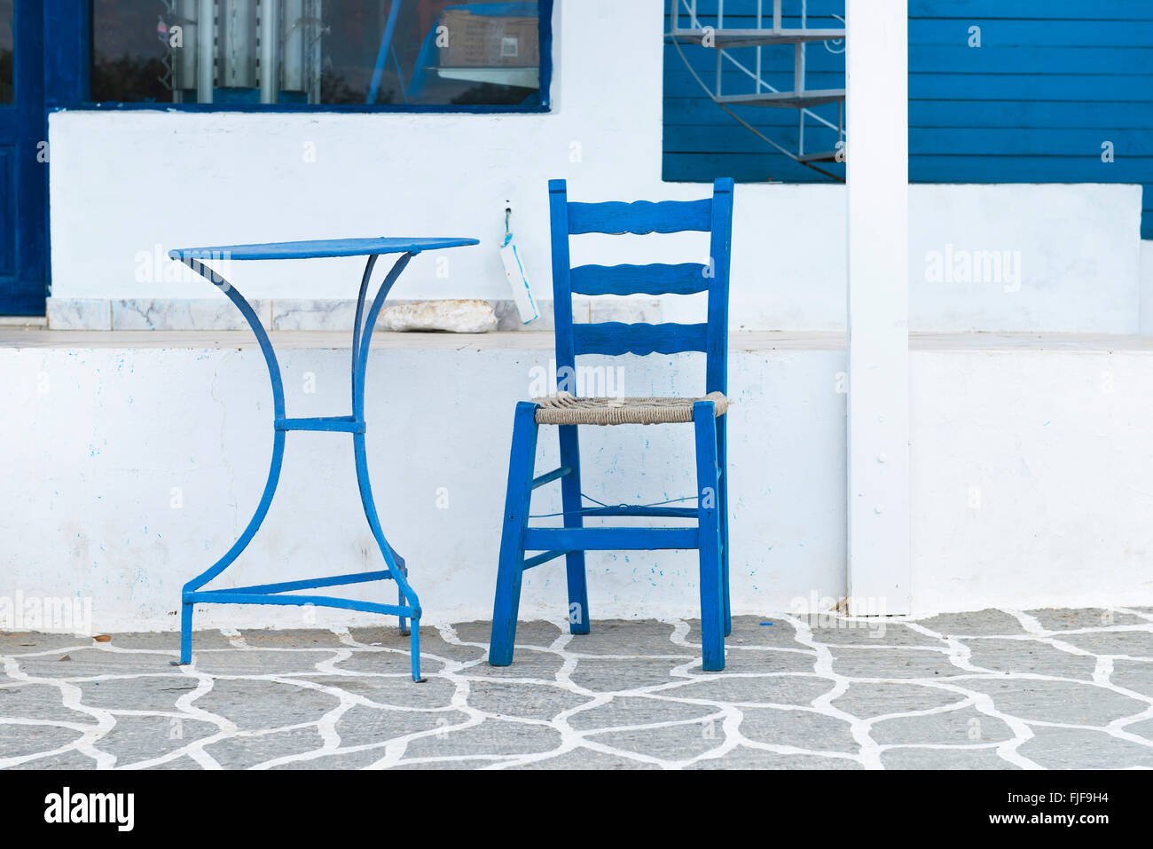 Blue chair and table on street of typical greek traditional village with white houses on Karpathos Island, Greece. Stock Photo