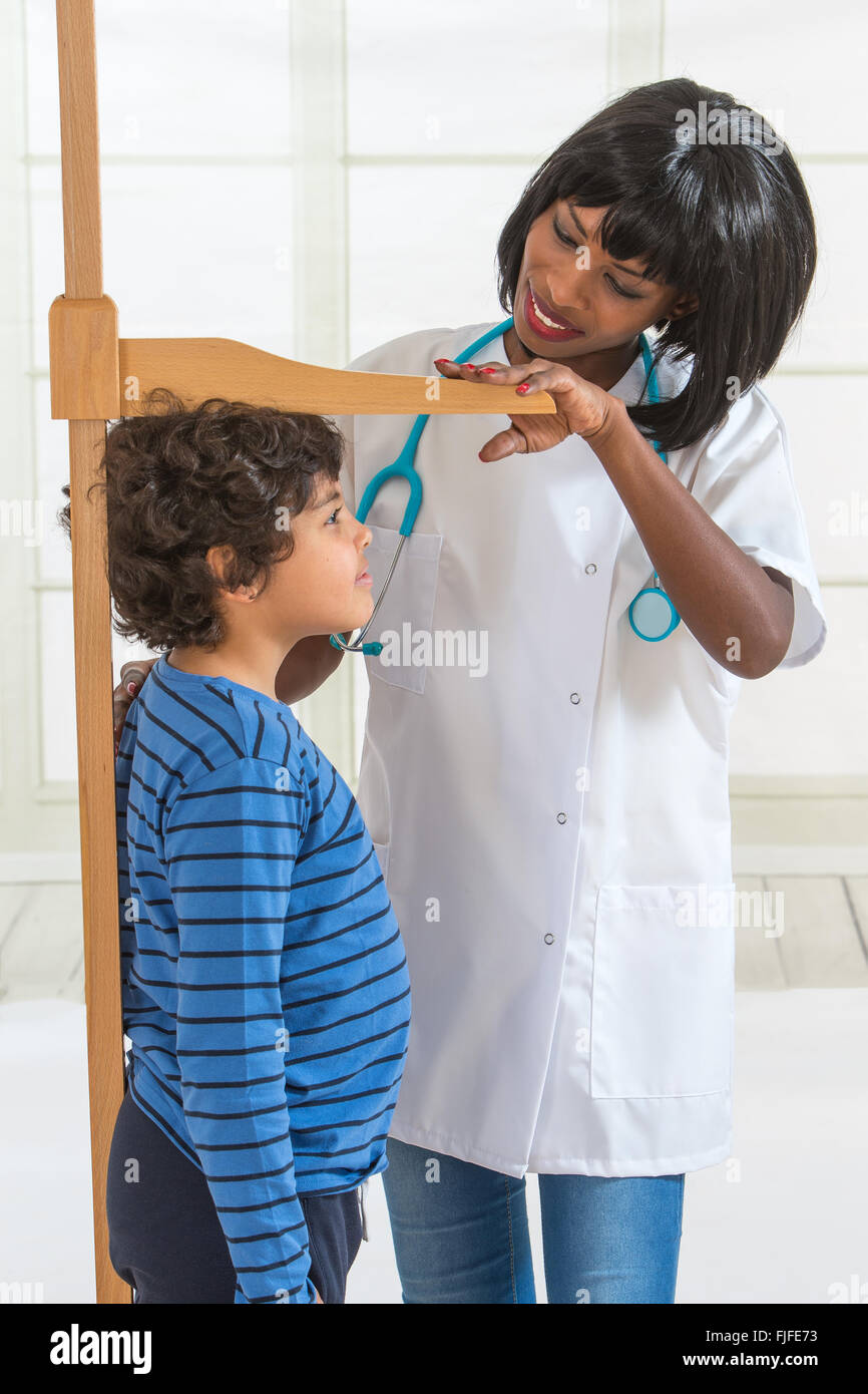 Doctor Measuring Height of Little Boy on Traditional Medical Scale Stock Photo