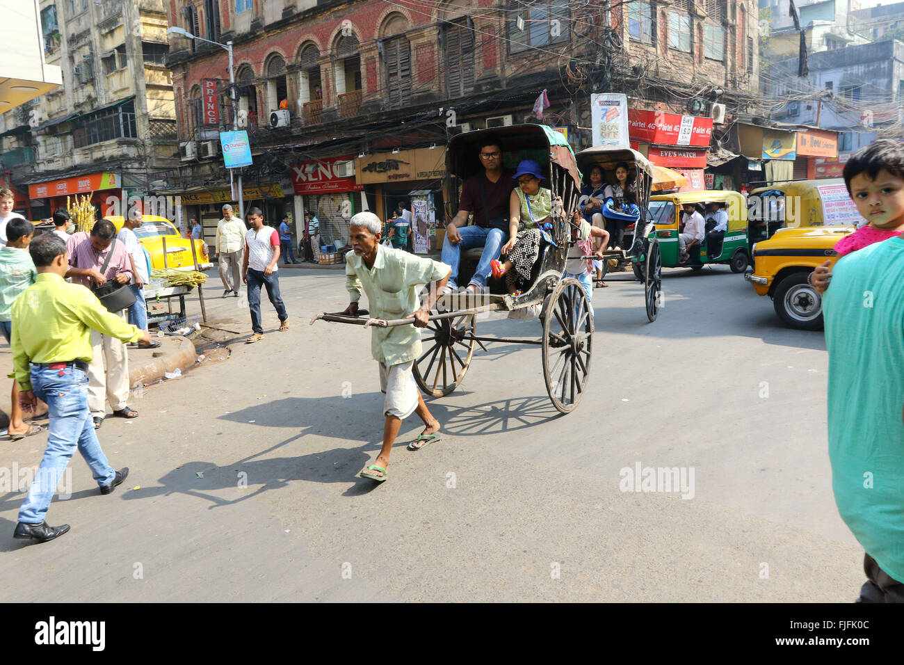 India, 19 February 2016. Hand pulling rickshaw puller pulling with passenger on road at street