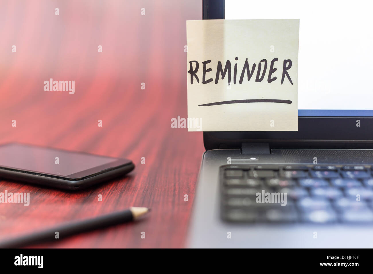 Yellow note with the word reminder taped on a laptop display Stock Photo