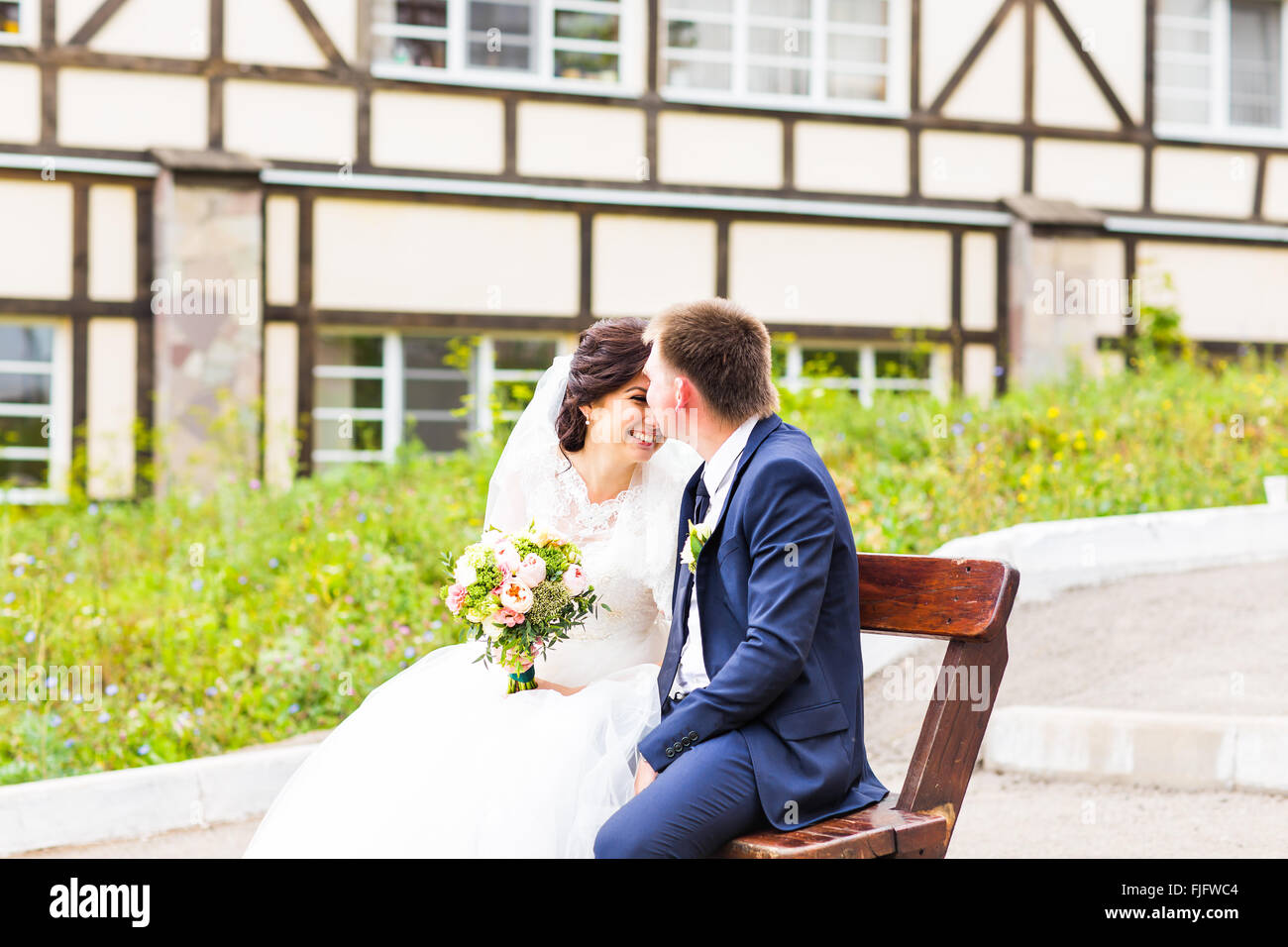 Romantic wedding couple sitting on a bench in the park Stock Photo - Alamy