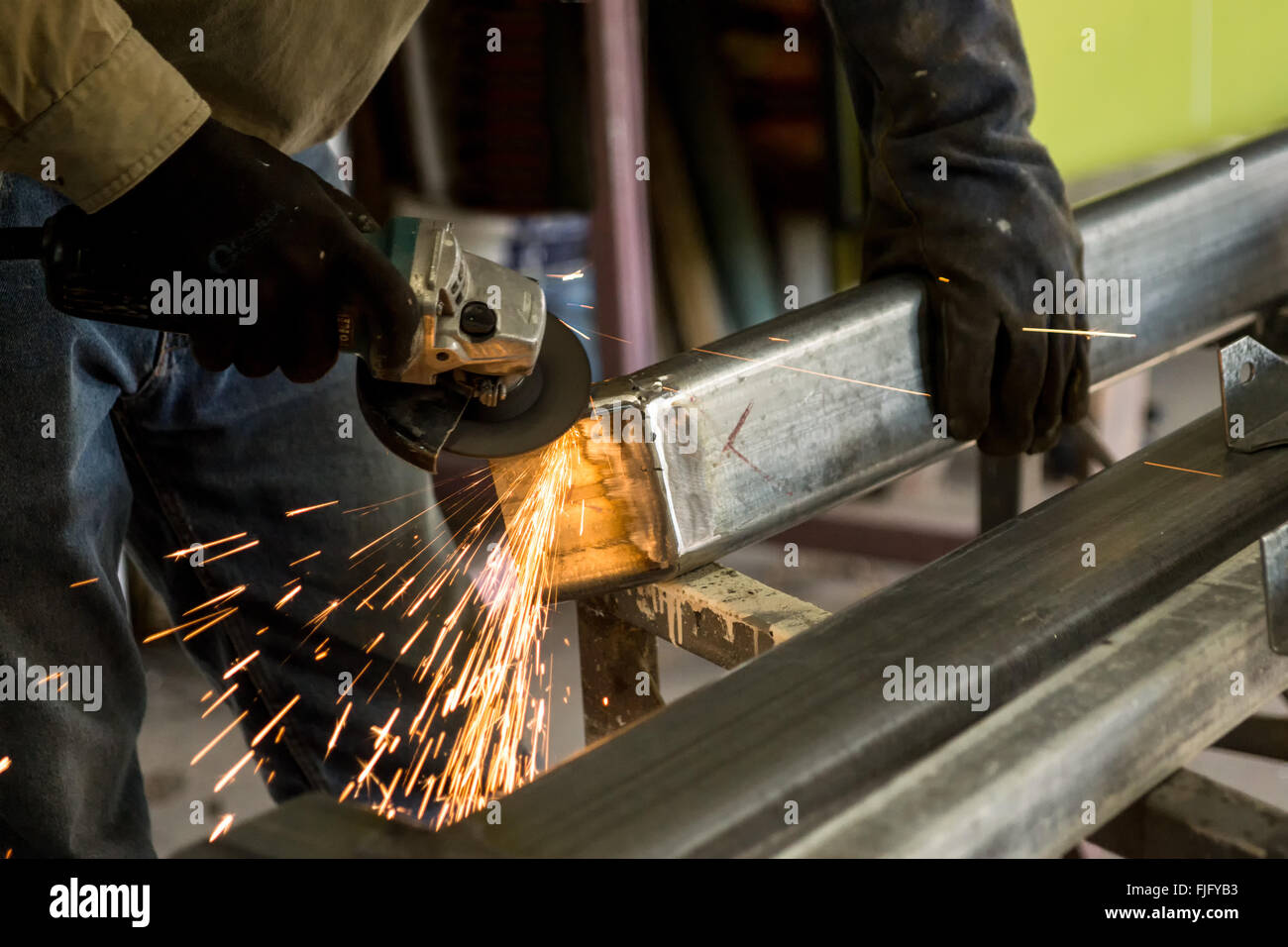 Man grinding steel with sparks flying after during fabricating steel house stumps Stock Photo