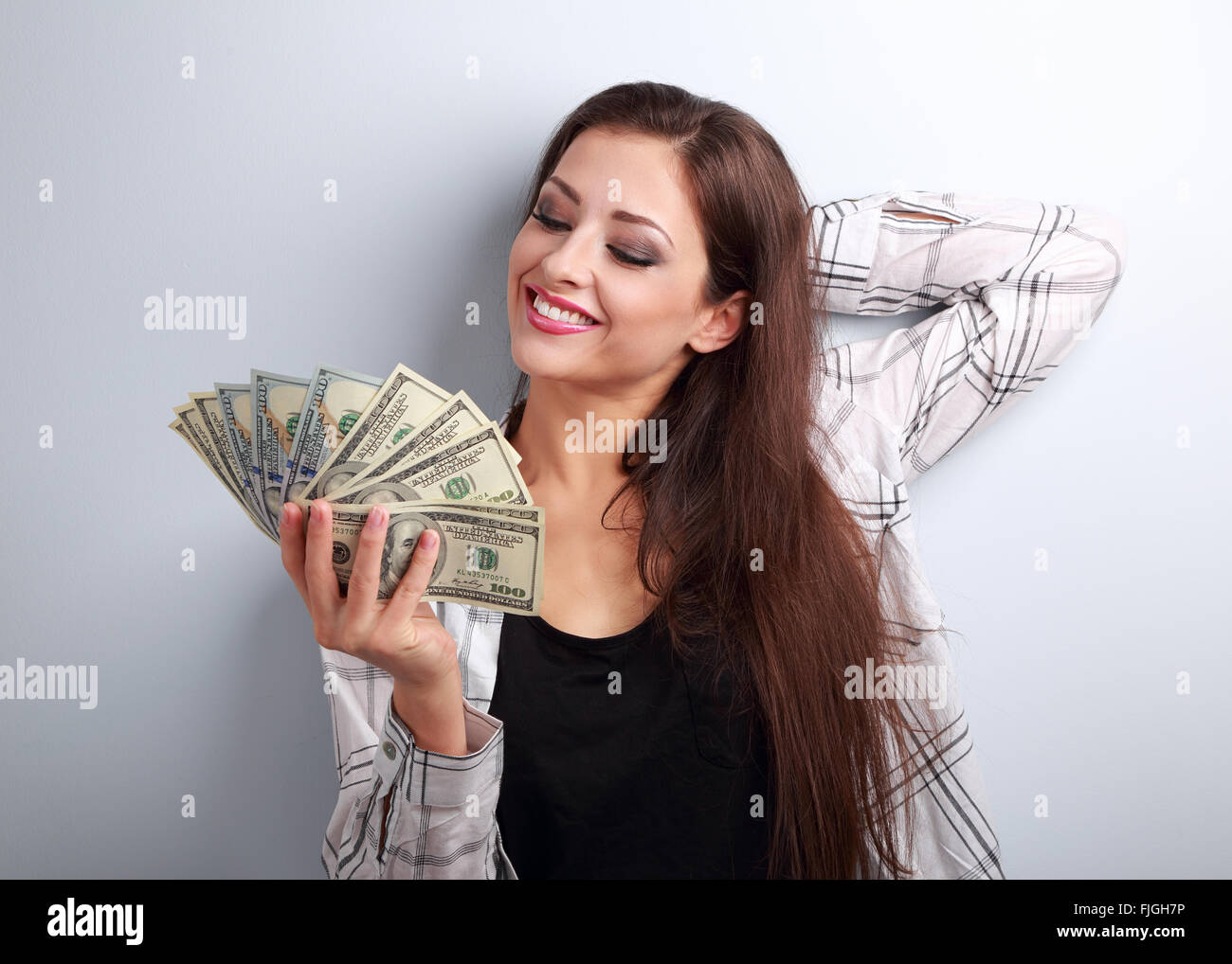 Relaxed young female model in casual clothing thinking how to spend money on blue background Stock Photo