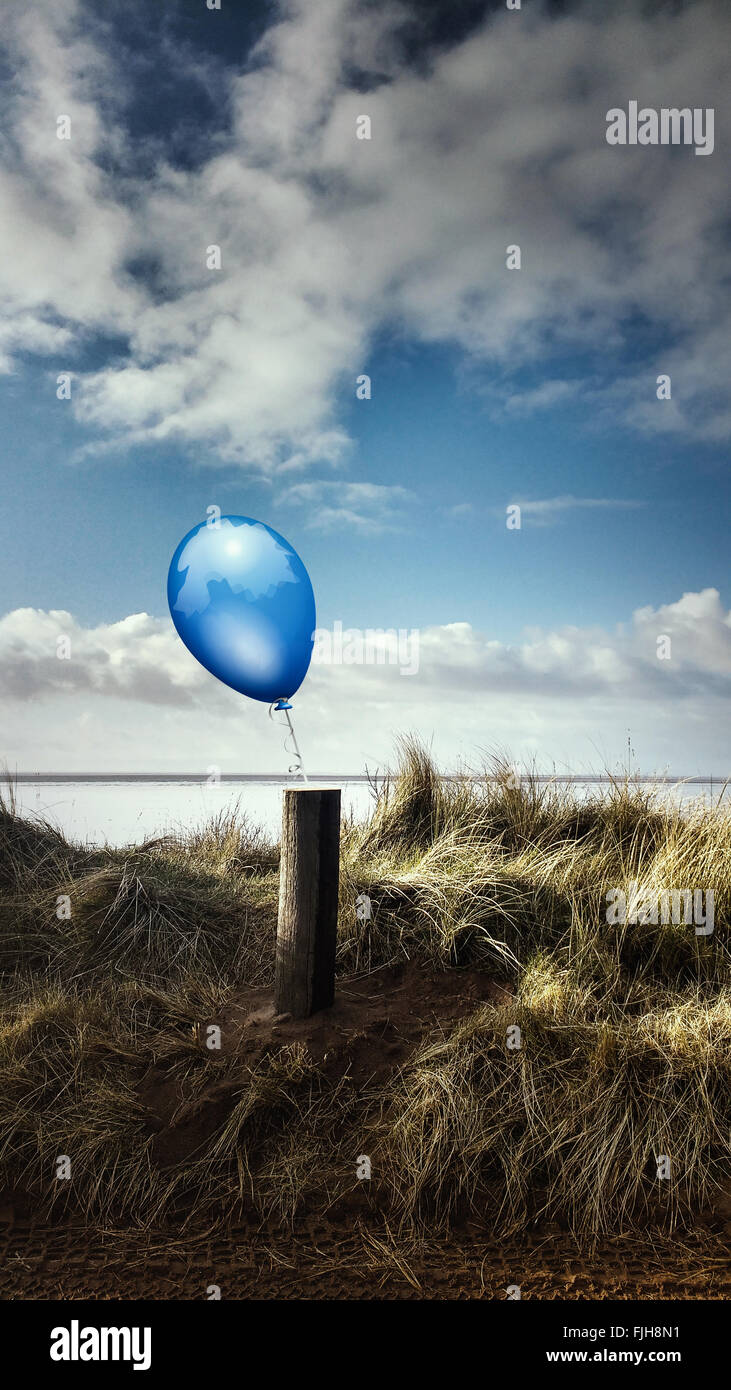 beach landscape with a wooden pole and a blue balloon attached to it Stock Photo