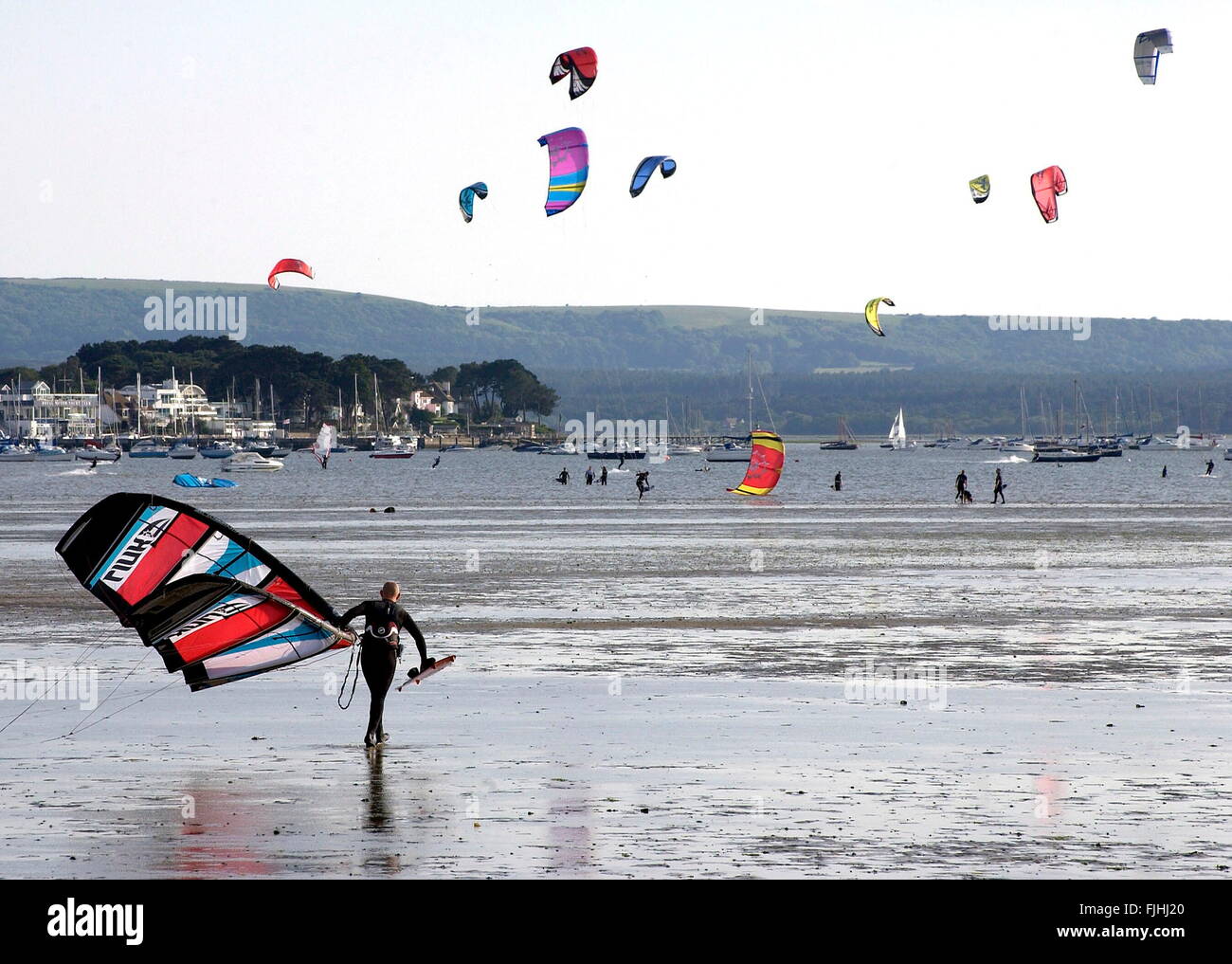 AJAXNETPHOTO. POOLE HARBOUR, ENGLAND. - KITE SURFERS - A SURFER HEADS OUT ACROSS THE MUDFLATS AT LOW TIDE. ROYAL MOTOR YACHT CLUB AT SANDBANKS CAN BE SEEN EXTREME LEFT. PHOTO:JONATHAN EASTLAND/AJAX  REF:TKZ 2007 1 Stock Photo