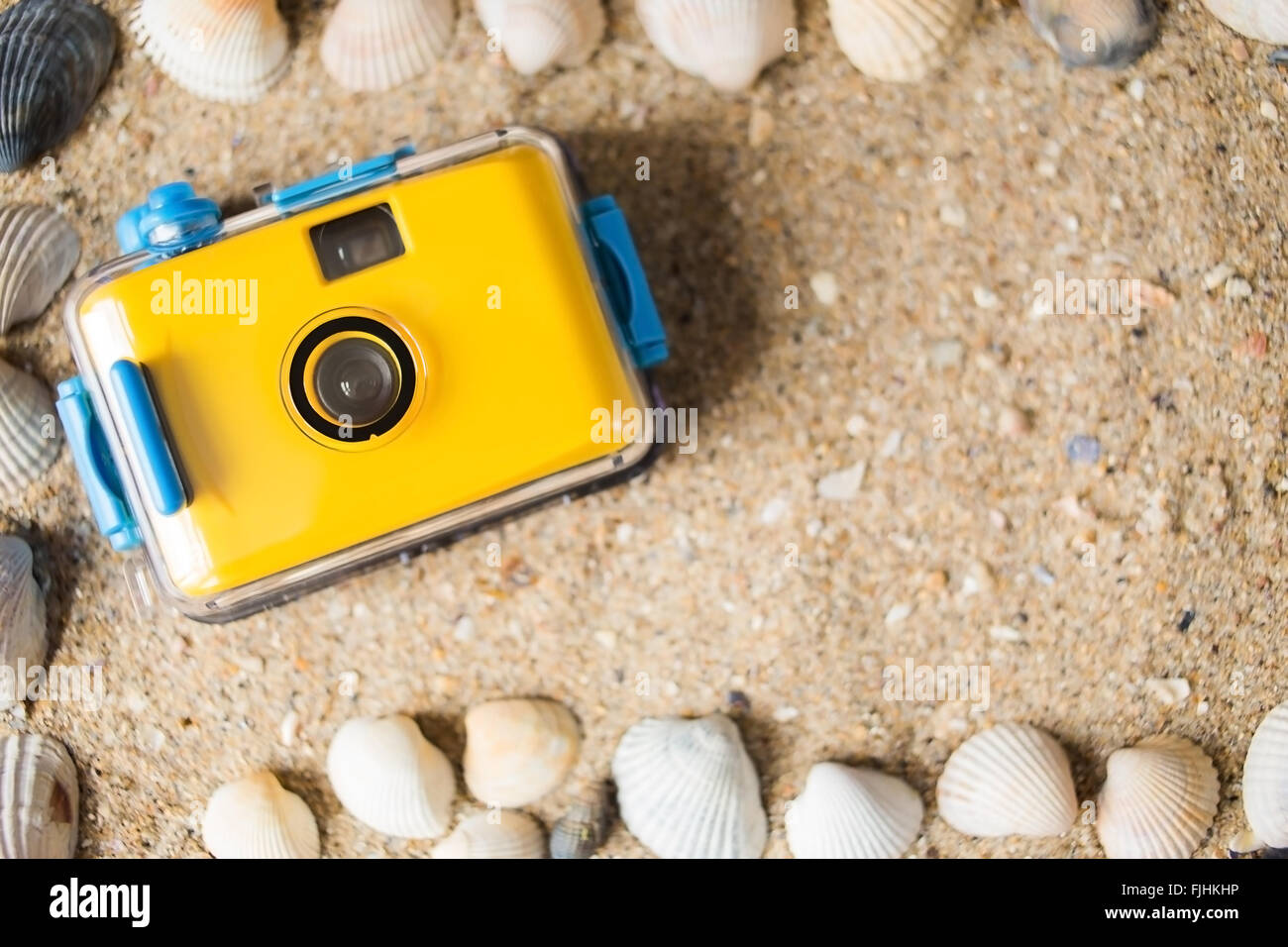 Yellow camera lying on sand at the beach Stock Photo