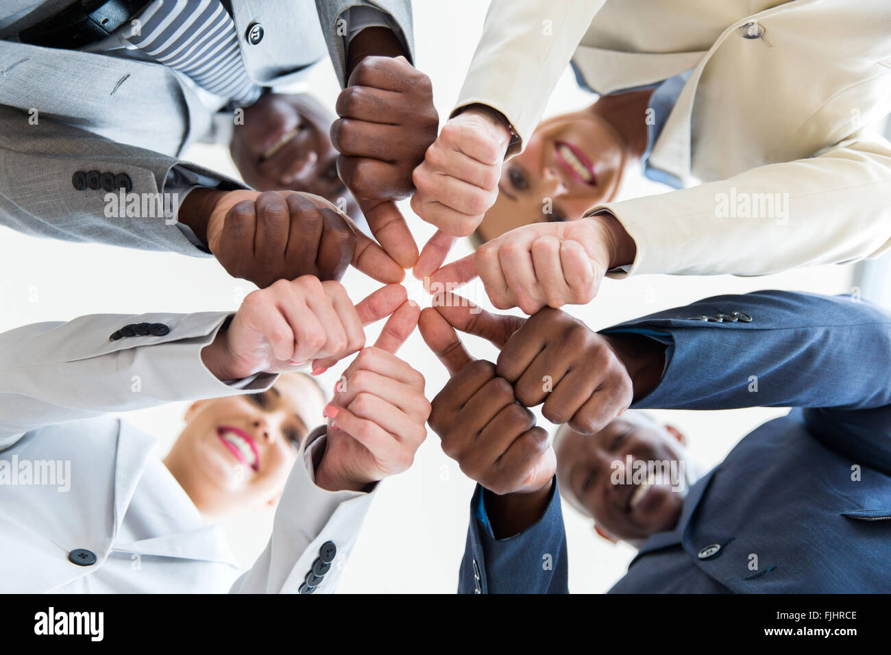 low angle view of multiracial co-workers with thumbs joined together Stock Photo