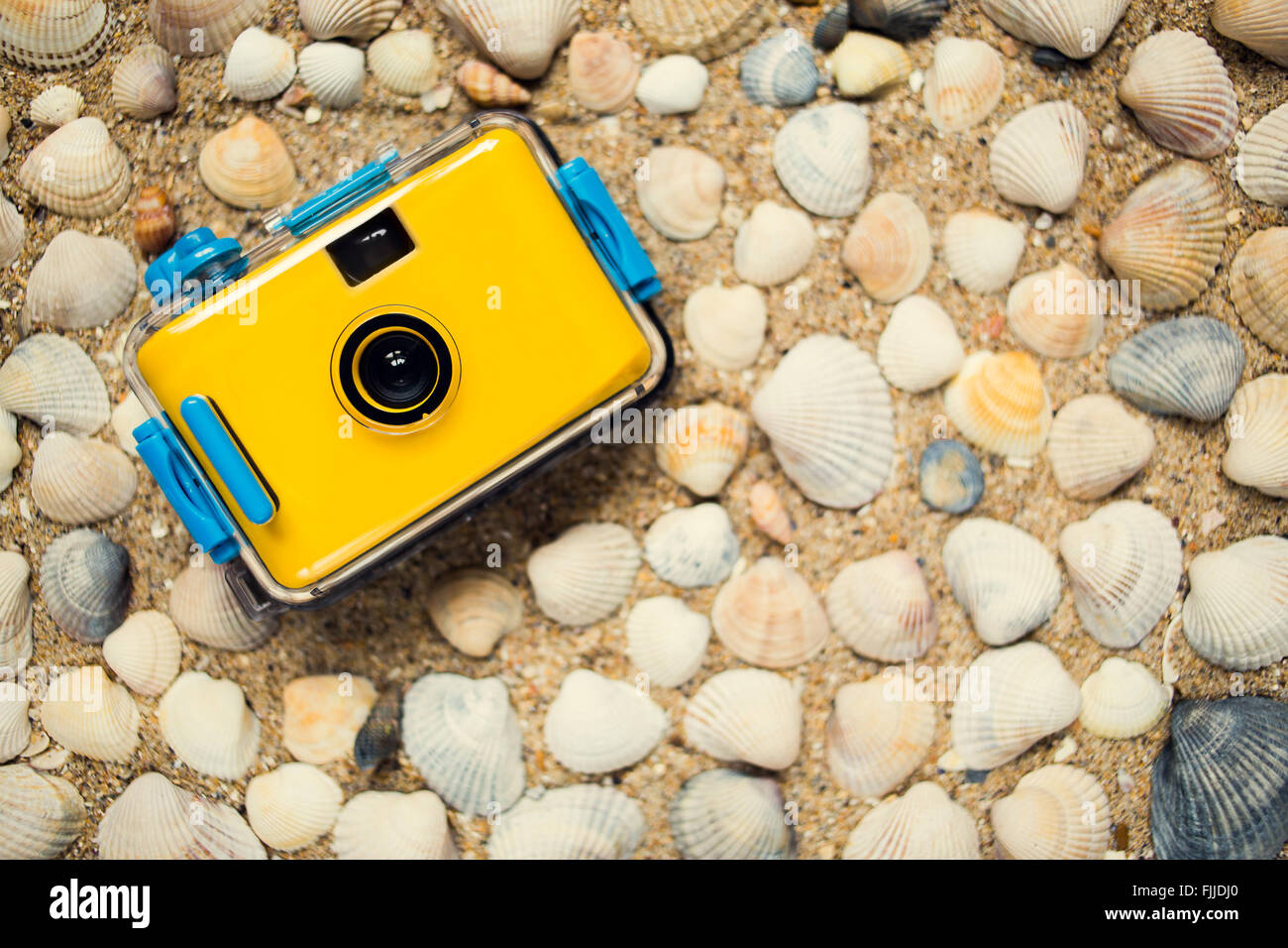 Yellow camera lying on sand at the beach Stock Photo