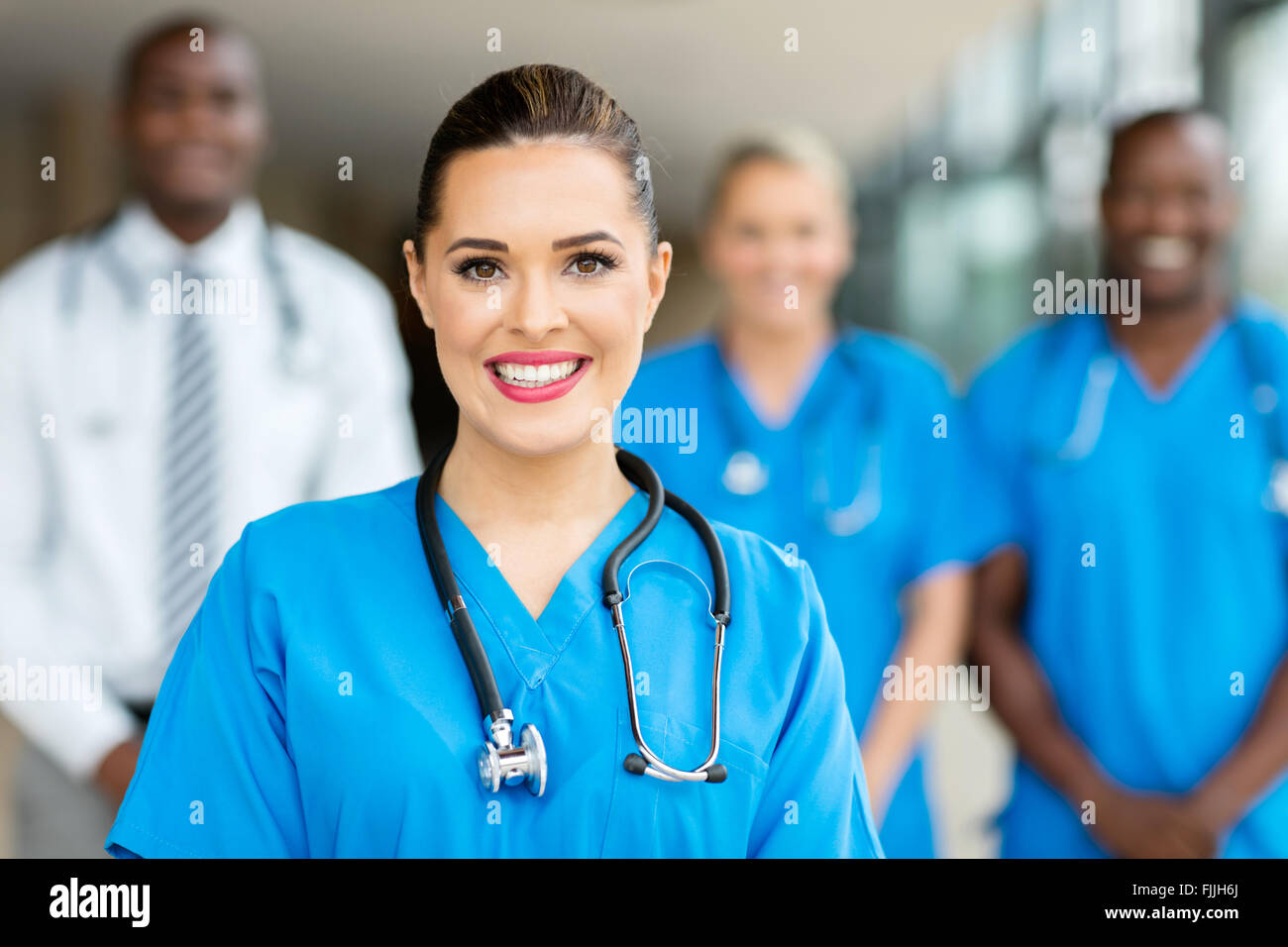 portrait of beautiful young female doctor standing with co-workers Stock Photo