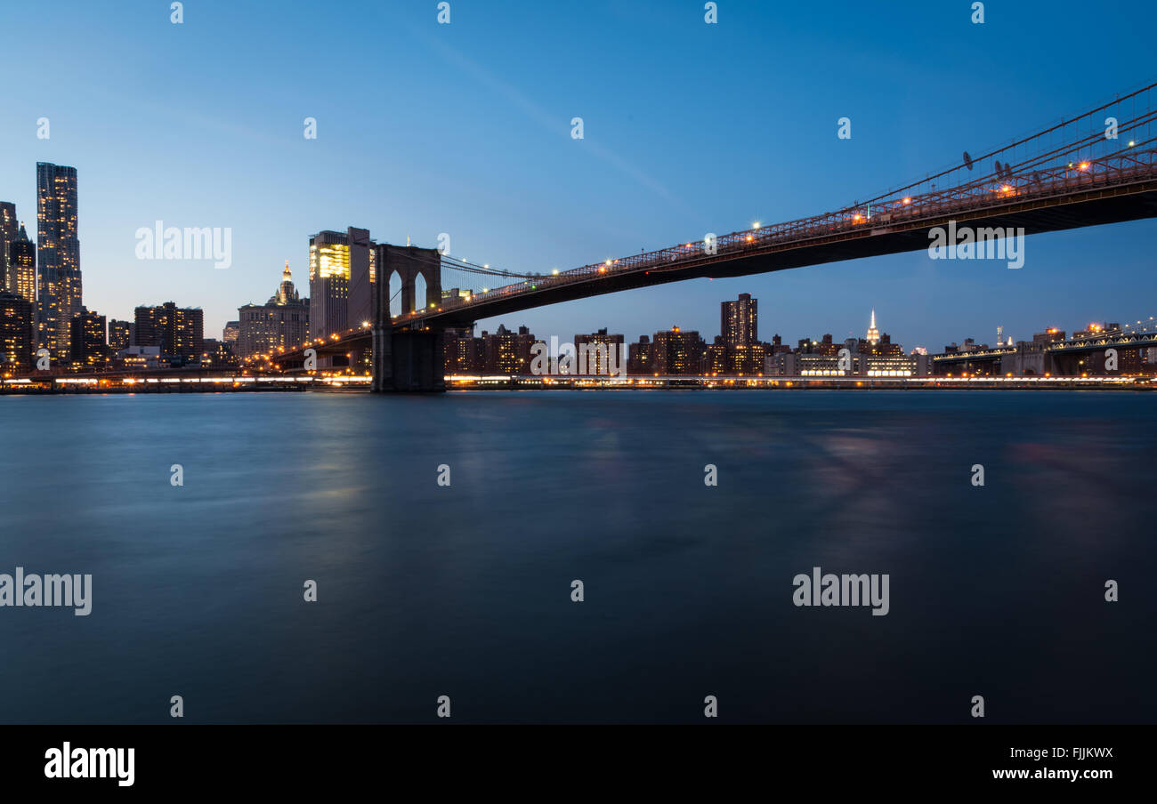 View of Brooklyn Bridge across the East River to Manhattan at twilight ...