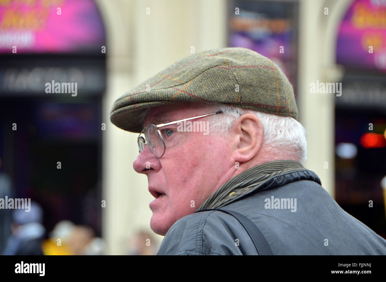 London, UK, 2 March 2016, Grey haired man wearing wax jacket and  flat cap in Piccadilly Circus. Stock Photo