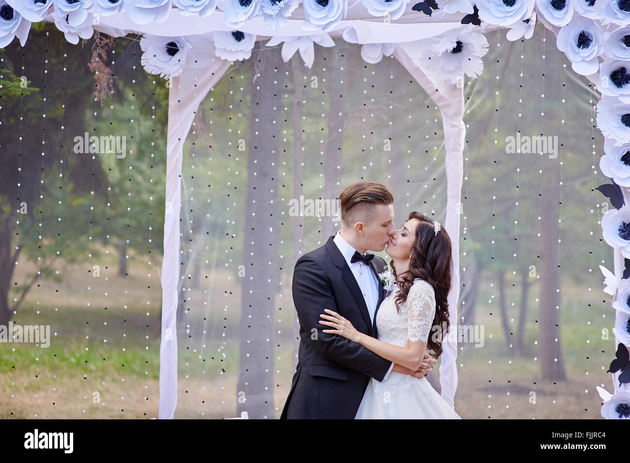 bride and groom stand near arch at wedding ceremony Stock Photo - Alamy