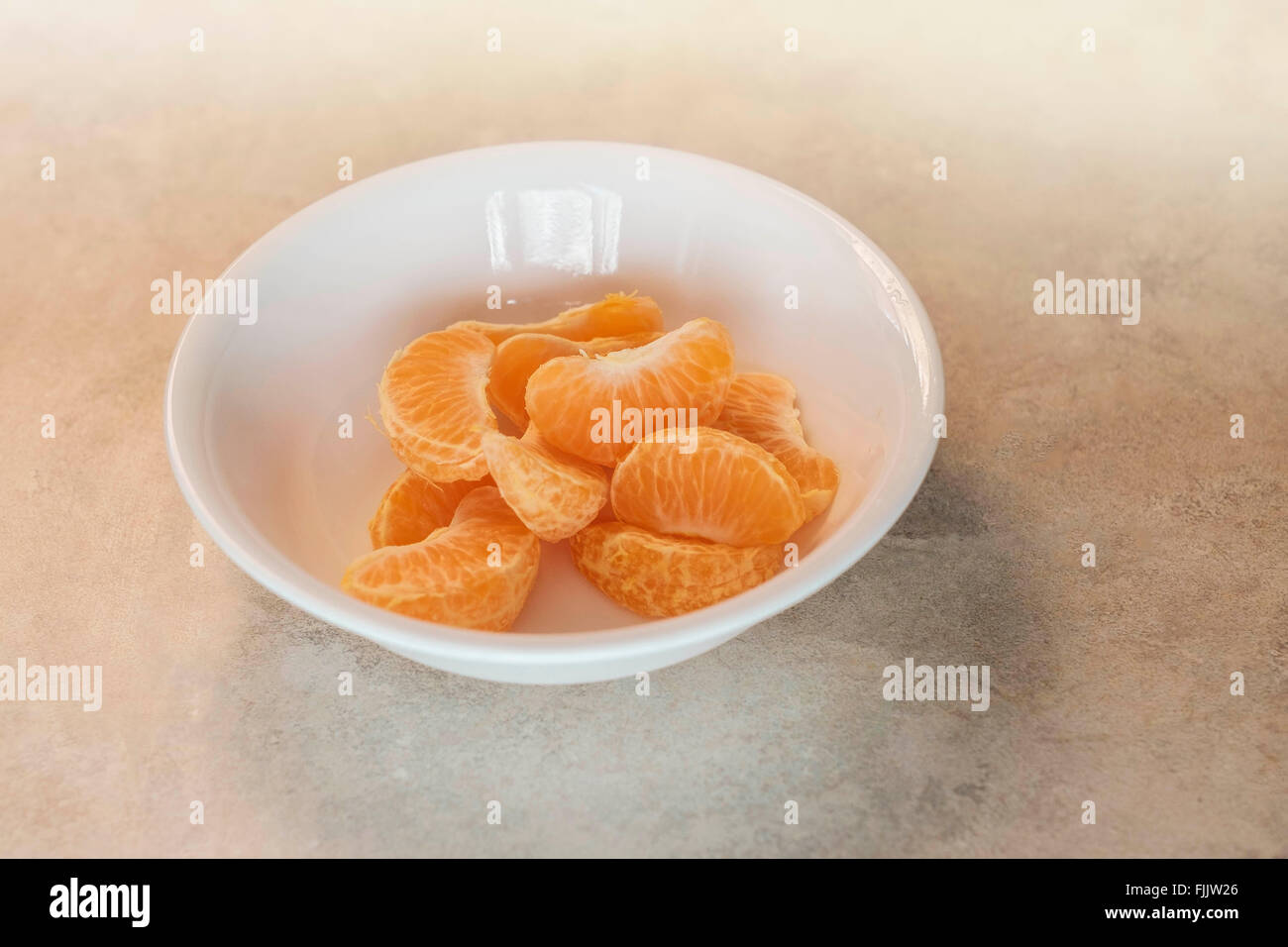 Mandarin orange slices piled in a white bowl. Stock Photo