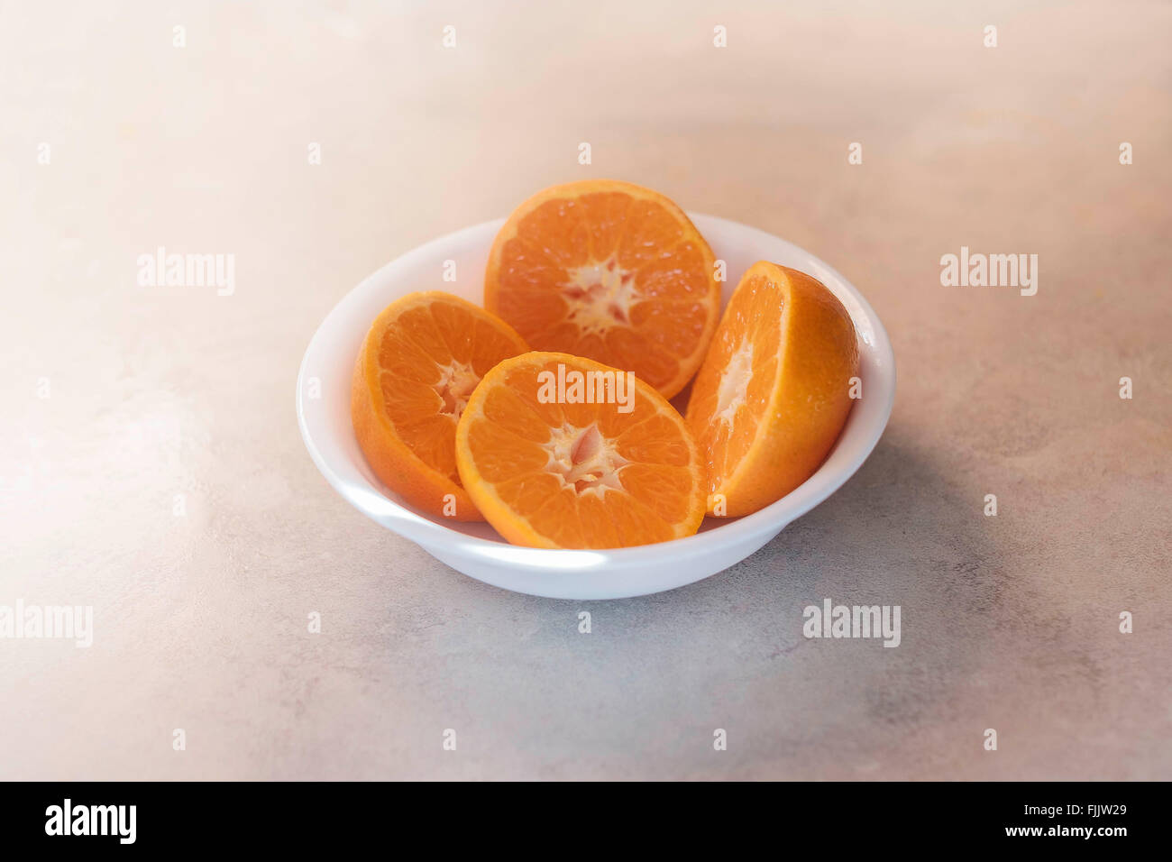 Four Mandarain orange halves in a white bowl. Stock Photo