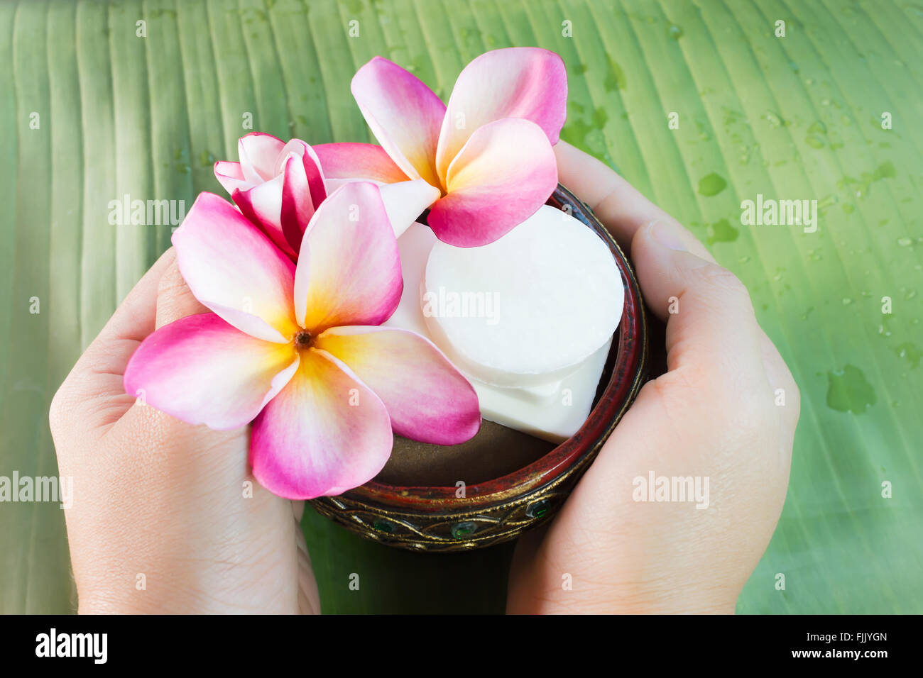 Hand take mini set of bath soap with flowers frangipani on green banana leaf with copy space Stock Photo