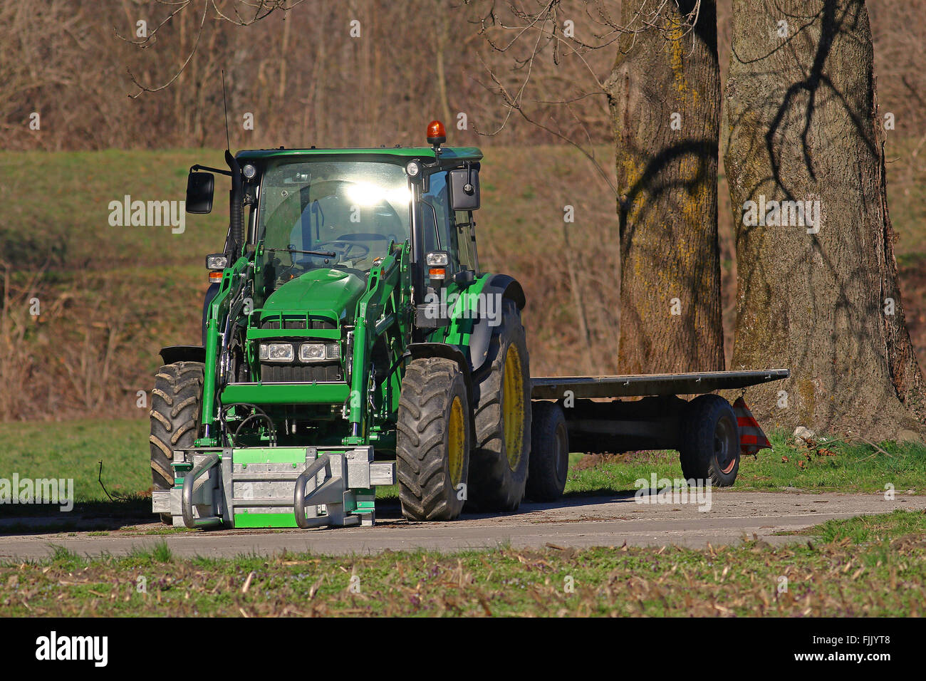 Green tractor and flatbed trailer Stock Photo