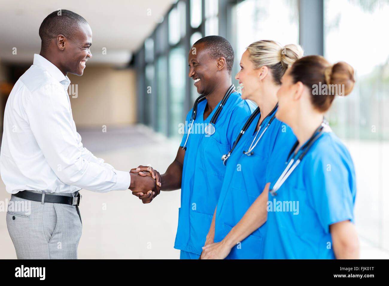 happy medical rep handshaking with group of doctors in hospital Stock Photo