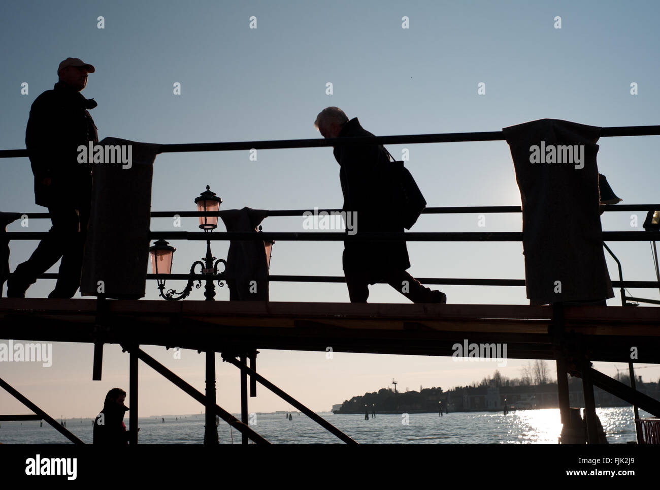Silhouette people crossing a bridge at sunset. Venice, Italy Stock Photo
