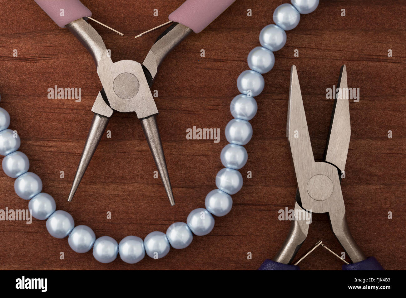 Two types of jewelry making pliers and a string of blue pearls for jewelry making. Stock Photo