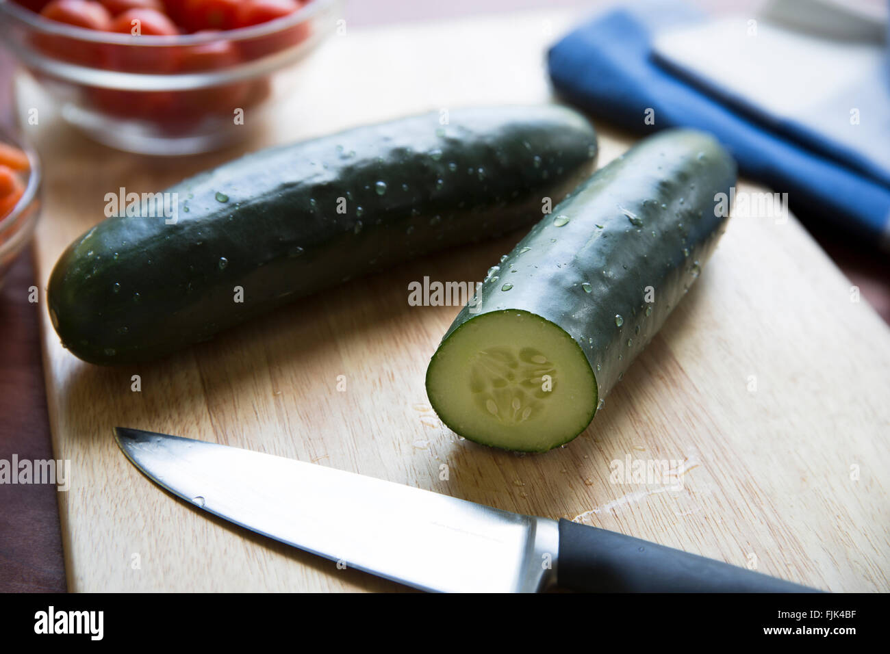 Cucumbers and knife on cutting board. Stock Photo