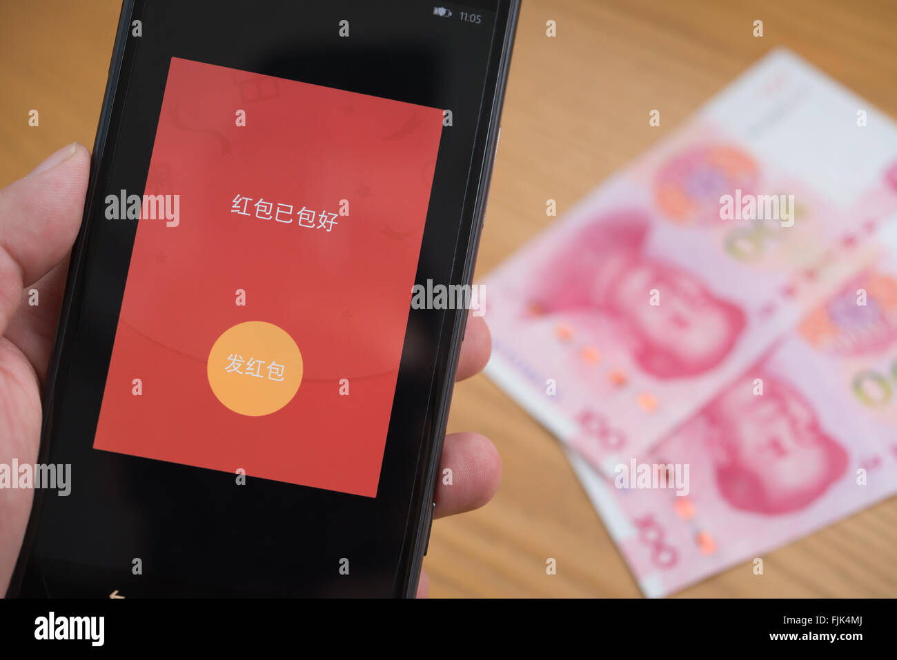 Zhongshan,China-Feb 21,2016:a red pocket on mobile is ready to be sent out on WeChat for Chinese new year with RMB on background Stock Photo