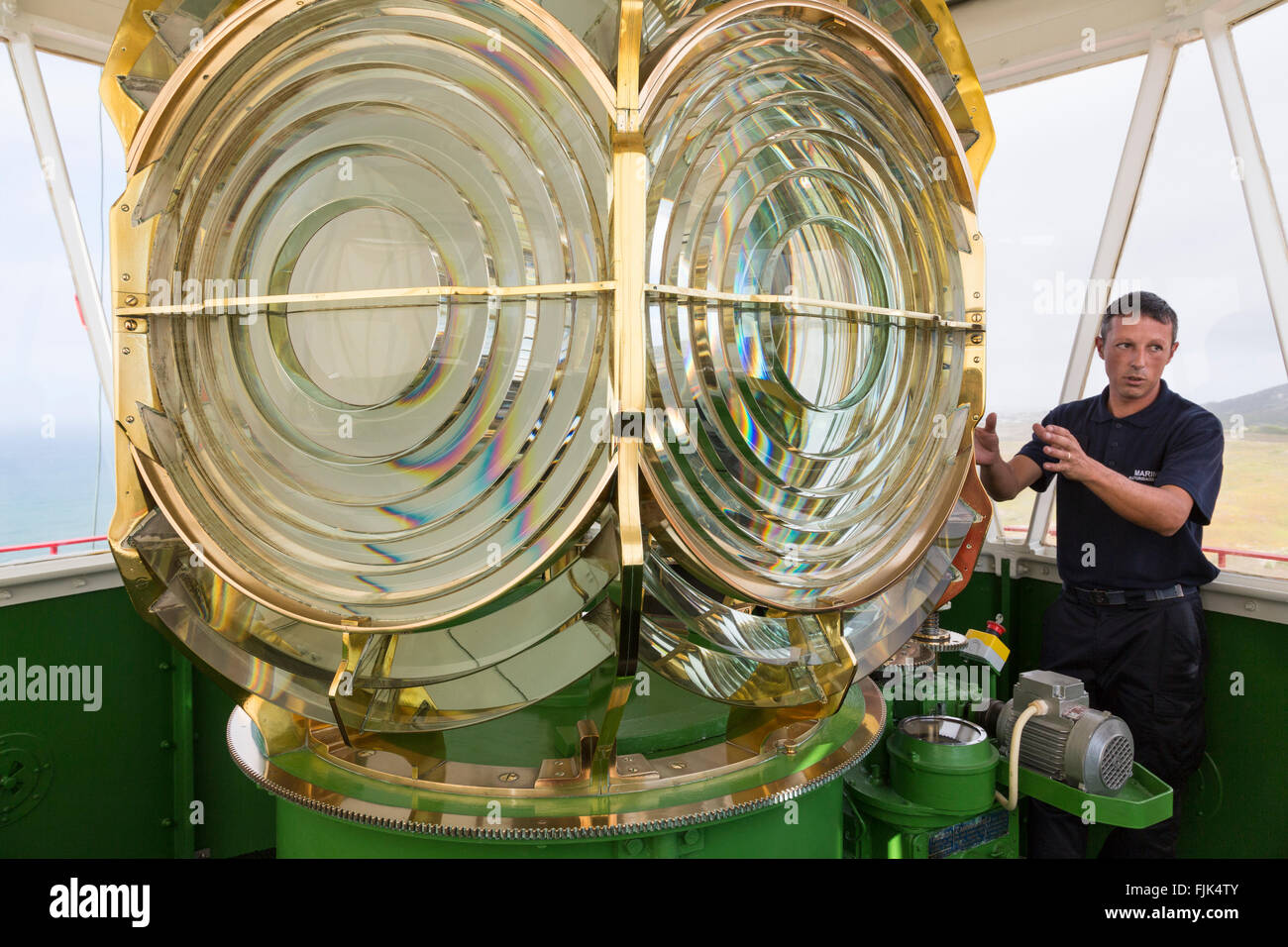 Portuguese naval officer giving a tour of the Cabo da Roca lighthouse in Colares, Portugal. The Fresnel lens magnifies a 3000 watt lamp. Stock Photo