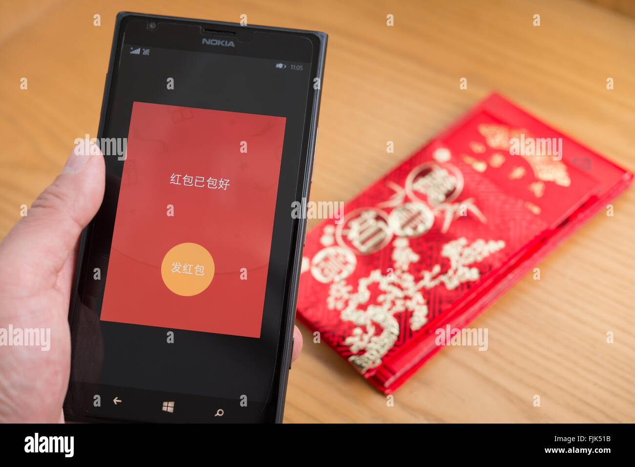 Zhongshan,China-Feb 21,2016:a red pocket on mobile is ready to be sent out on WeChat for Chinese new year with real red pockets Stock Photo