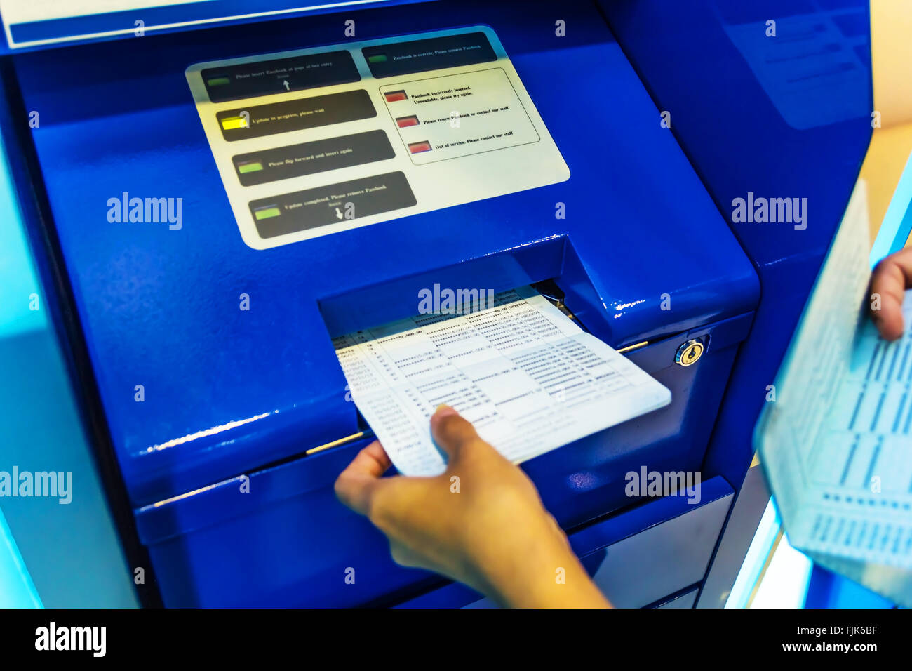 A photo of Hand on Saving deposit passbook Updating with Passbook Update Machines (PUMs) Stock Photo