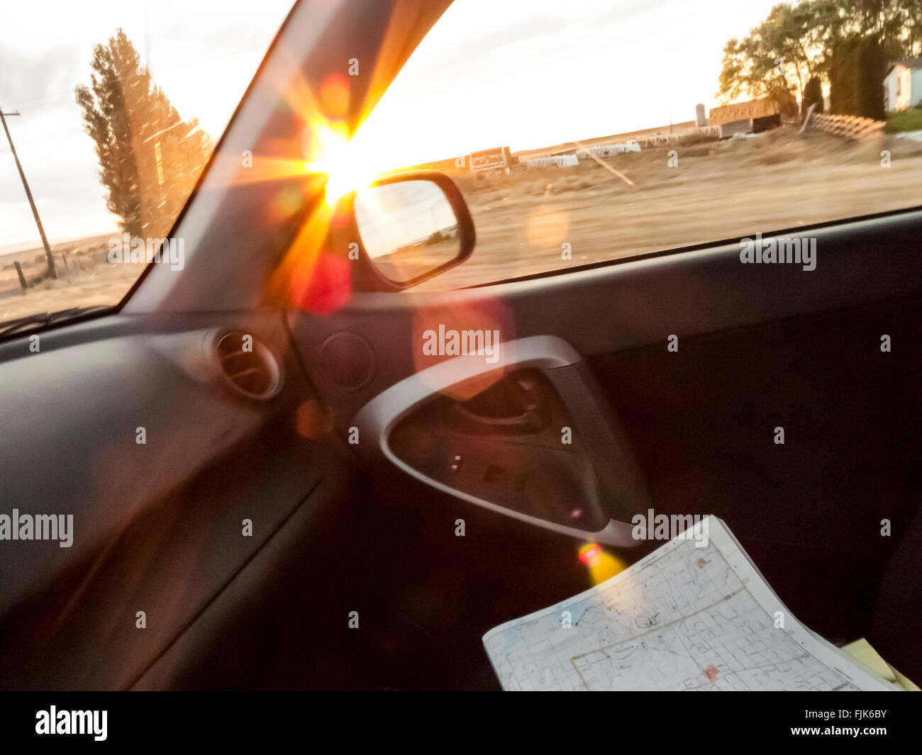 Road map on automobile passenger seat with sunset view through open window. Summer road trips exploring America by car. Stock Photo