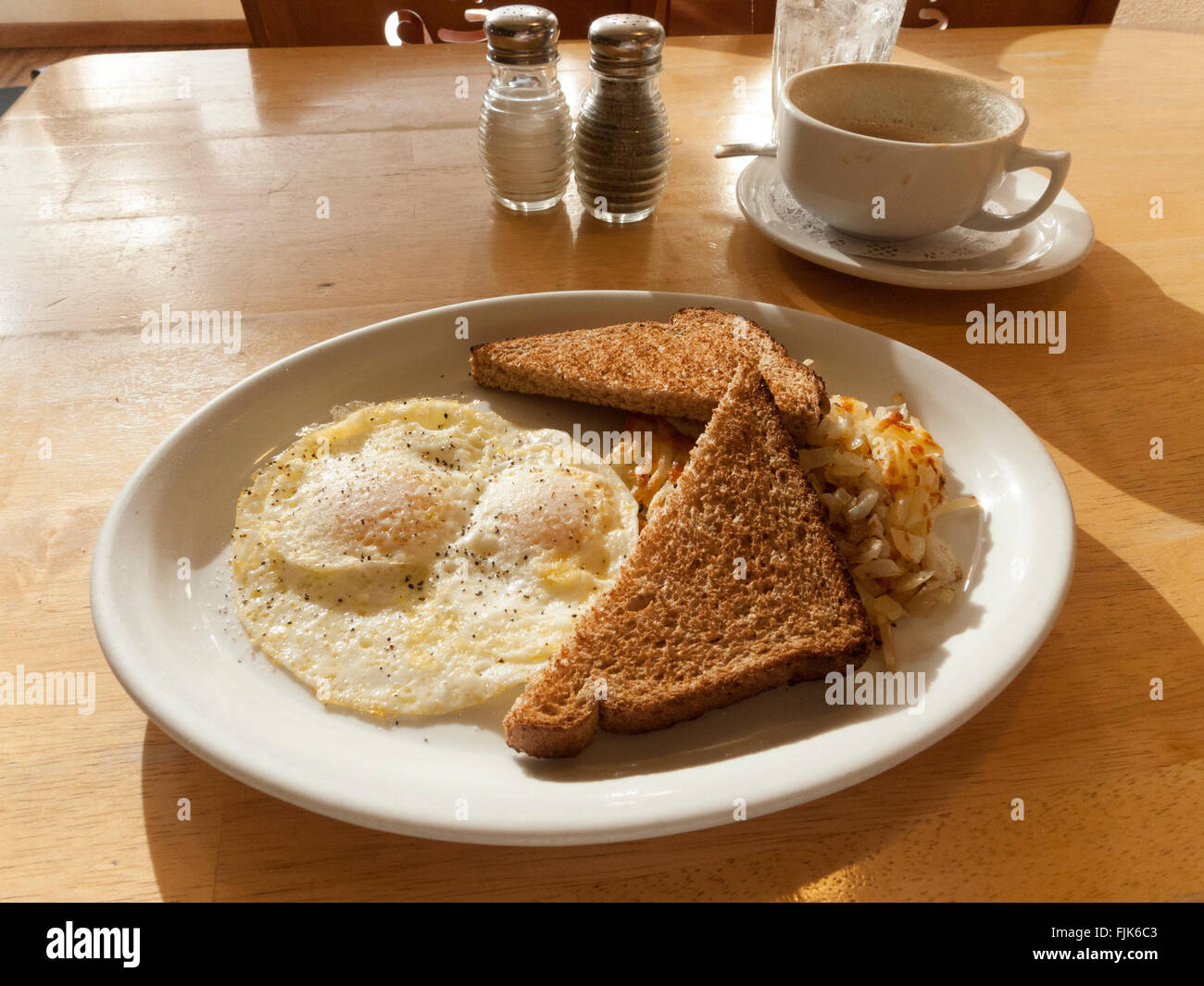 Traditional American country breakfast of eggs, hashed brown potatoes, toast and coffee in a diner restaurant Stock Photo