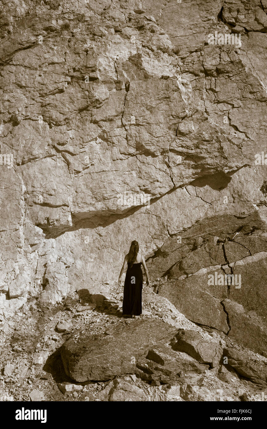 Rear view of woman standing in front of solid rock wall, Arizona, USA. Facing difficulties, challenges, obstacles, barriers concepts. Stock Photo