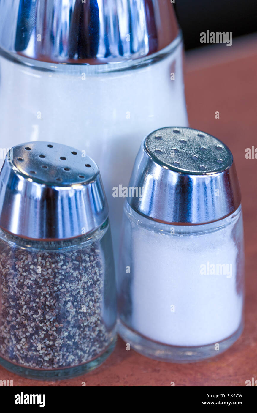 Salt and pepper shakers and sugar dispensers on counter in a classic American cafe diner restaurant. Food service icon. Stock Photo