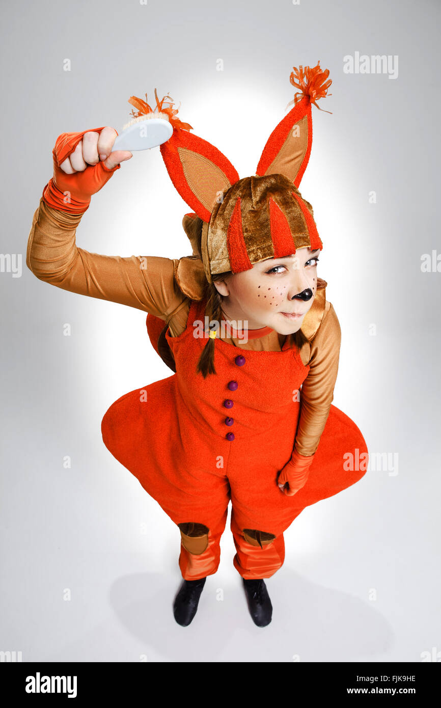 Young woman in the image of red squirrel combing on white background. The children's concept of the mode of the day Stock Photo